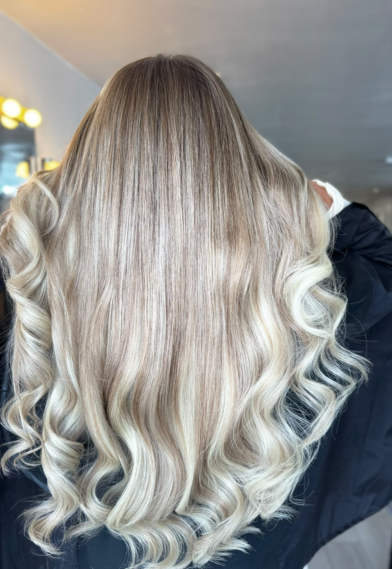 Blonde hair extensions curled into bouncy waves, back view