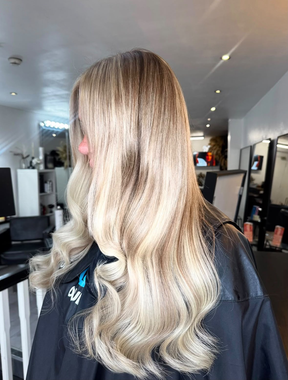 Blonde balayage hair extensions styled in soft waves, side view