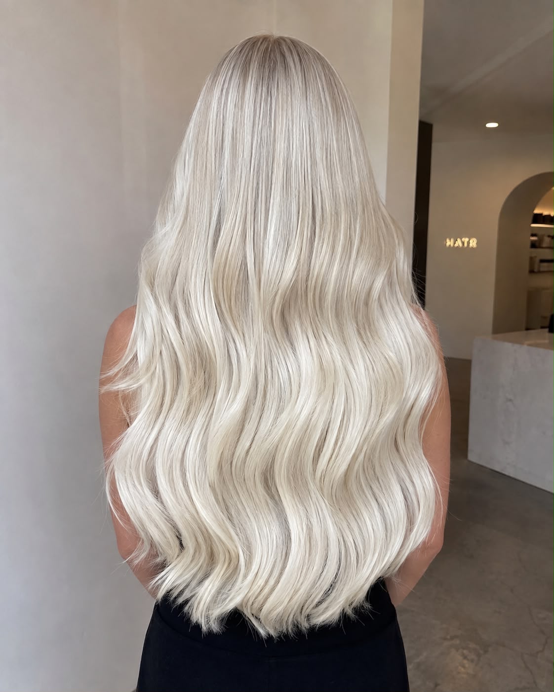 Long, flowing blonde human hair extensions styled in soft waves